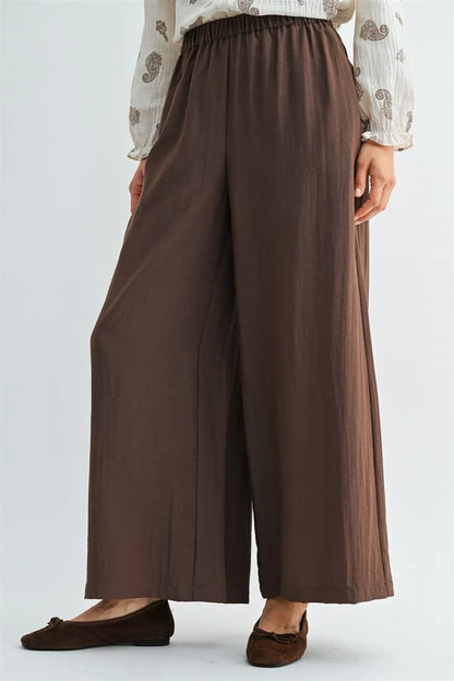 Brown wide leg pants with elastic waist and side pockets made of soft flowing fabric for comfortable wear