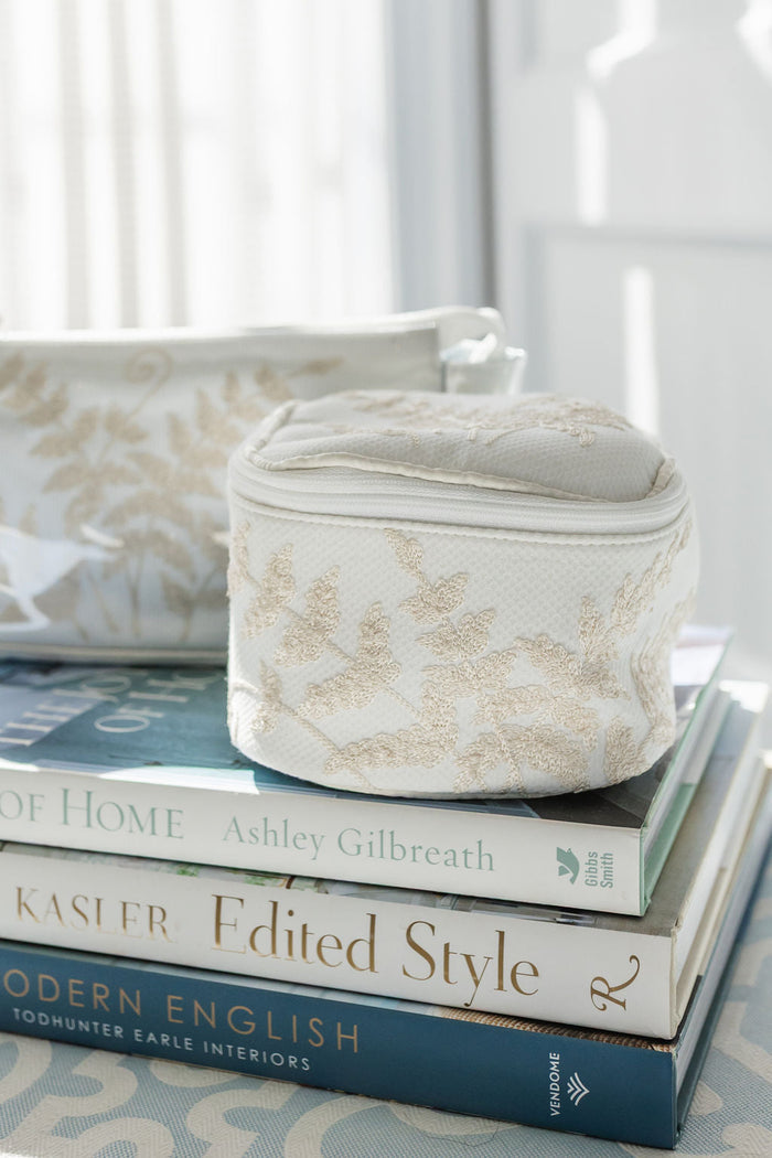 Fern case and coordinating makeup bag on a stack of books by Lenora