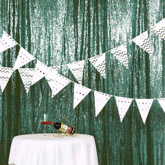 Party decorations with bunting and wine on a table against a sparkling green backdrop.