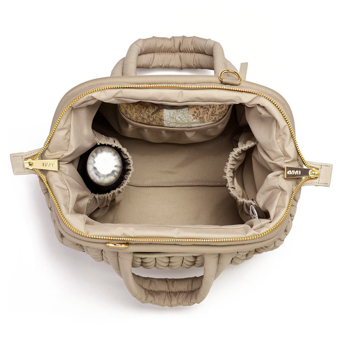 Top-down view of the Paige Mini Beige, showing the wide Mary Poppins style opening, with 2 of the 3 interior pockets packed with baby items.