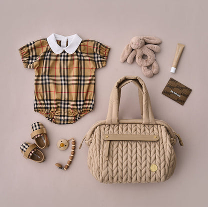 Flat-lay of the Paige Mini Beige from the front, showing carry handles and front mom pocket, alongside matching baby items.