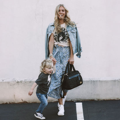 Mom carrying Paige Mini Black by the handles while walking and holding her toddler's hand.